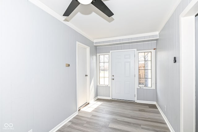 entryway with ceiling fan, wood finished floors, baseboards, and ornamental molding