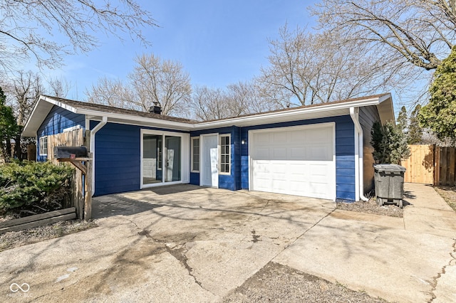 ranch-style house featuring an attached garage, driveway, and fence