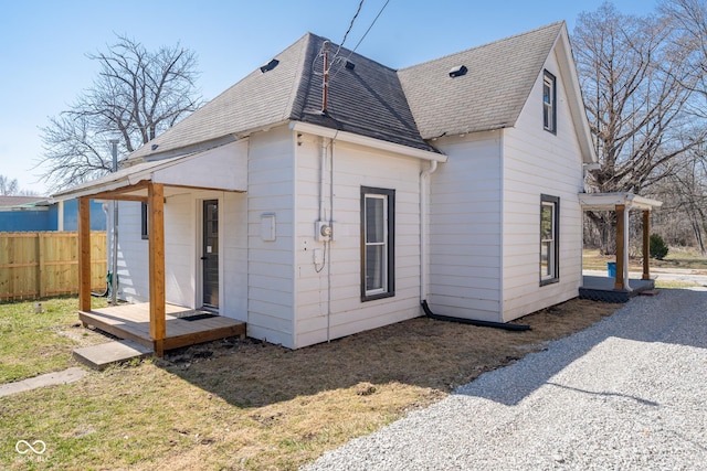 rear view of house with fence and roof with shingles