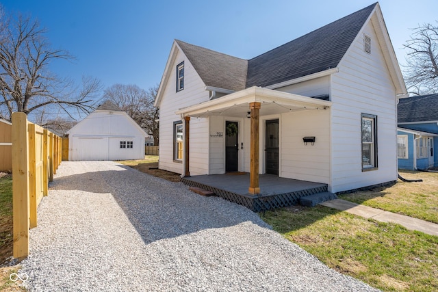 view of front of home with an outbuilding, roof with shingles, covered porch, and fence