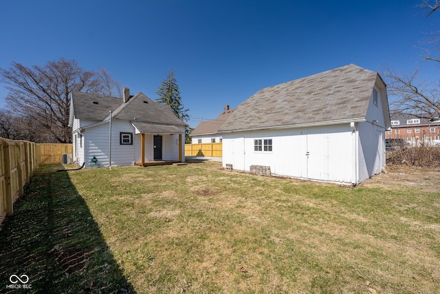 back of property featuring an outdoor structure, a yard, and a fenced backyard