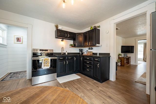 kitchen featuring a sink, dark countertops, stainless steel electric range, and light wood finished floors