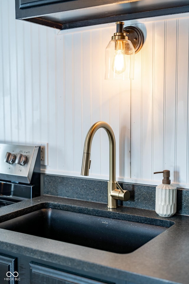 interior details with a sink, dark countertops, and white cabinetry