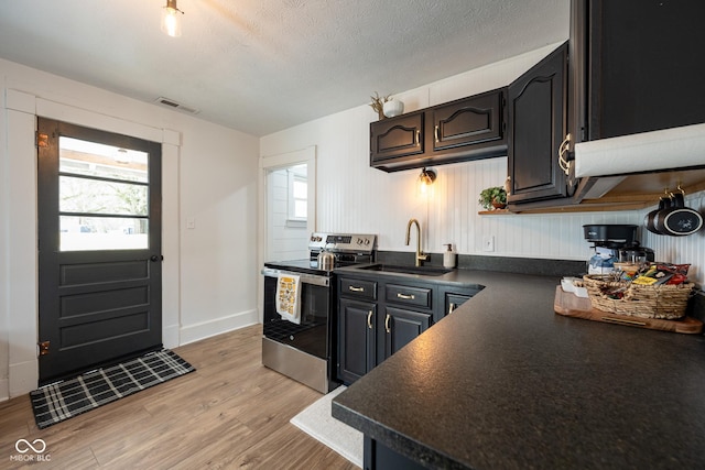 kitchen featuring dark countertops, stainless steel electric stove, light wood-style floors, and visible vents