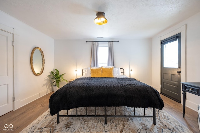 bedroom featuring a textured ceiling, baseboards, and wood finished floors