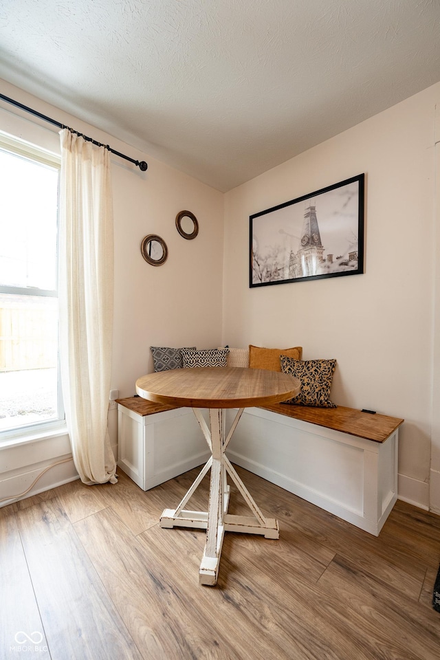 dining area with breakfast area, baseboards, a textured ceiling, and light wood-style flooring