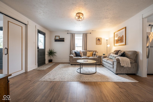 living room with a textured ceiling, baseboards, and wood finished floors