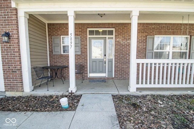 property entrance with brick siding and covered porch