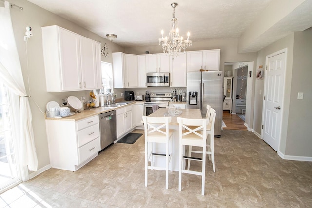 kitchen featuring a kitchen breakfast bar, appliances with stainless steel finishes, a chandelier, and white cabinets