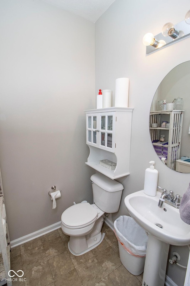 bathroom featuring tile patterned flooring, toilet, baseboards, and a sink