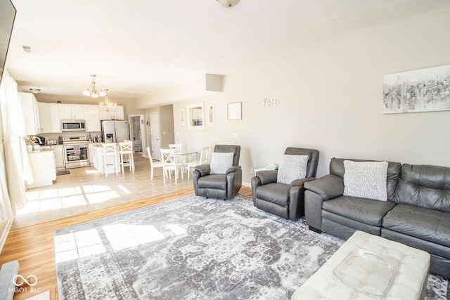 living room featuring visible vents, light wood-style flooring, baseboards, and an inviting chandelier