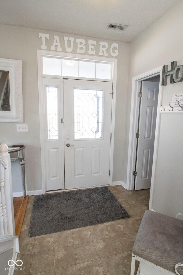 foyer entrance featuring visible vents and baseboards