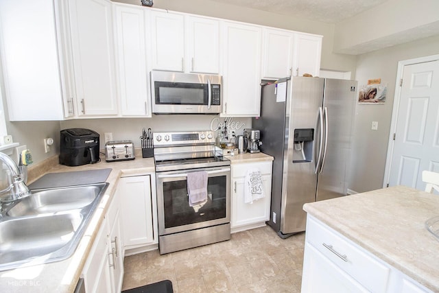 kitchen with white cabinetry, light countertops, appliances with stainless steel finishes, and a sink