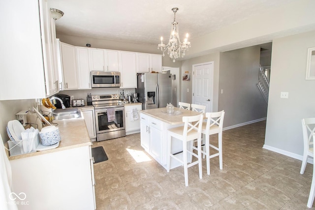 kitchen with white cabinets, appliances with stainless steel finishes, light countertops, and a sink