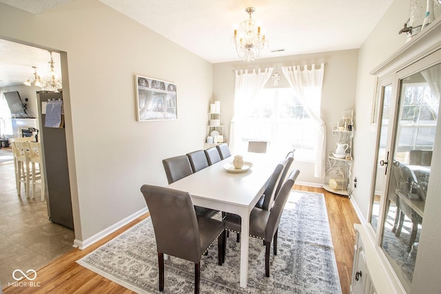 dining area featuring light wood-style flooring, baseboards, and a chandelier