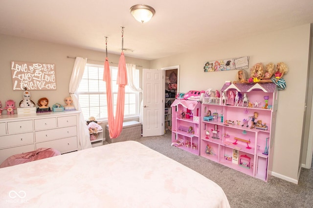 carpeted bedroom with a walk in closet and baseboards