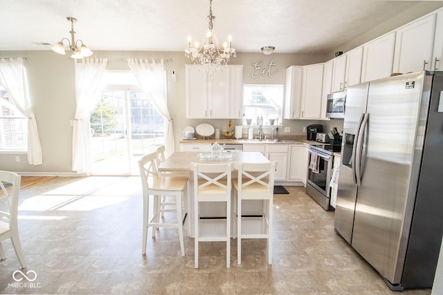 kitchen featuring a sink, stainless steel appliances, a chandelier, and white cabinets