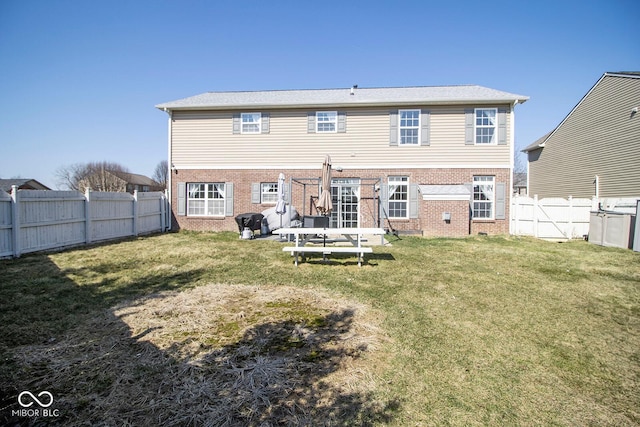 rear view of house featuring brick siding, a yard, and a fenced backyard