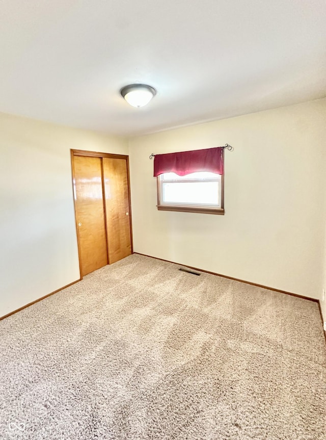 unfurnished bedroom featuring visible vents, baseboards, a closet, and carpet floors