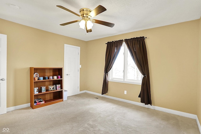 carpeted empty room with visible vents, a textured ceiling, baseboards, and ceiling fan