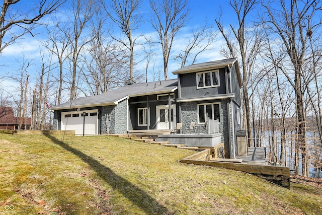 view of front of property featuring stone siding, a front yard, and a garage