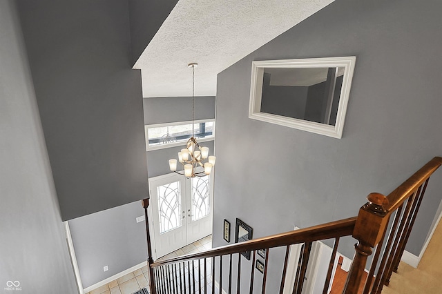 stairway with a chandelier, a textured ceiling, a high ceiling, and baseboards