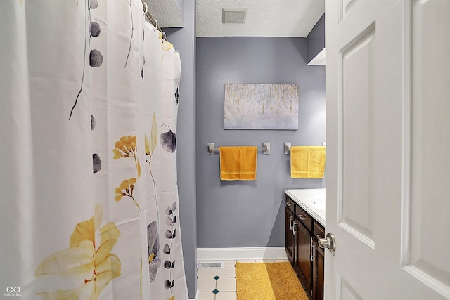 bathroom featuring visible vents, a textured ceiling, tile patterned flooring, baseboards, and vanity