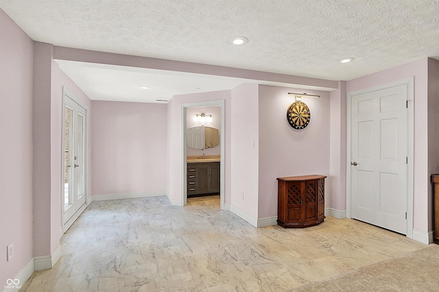 empty room featuring baseboards, recessed lighting, marble finish floor, a textured ceiling, and a sink