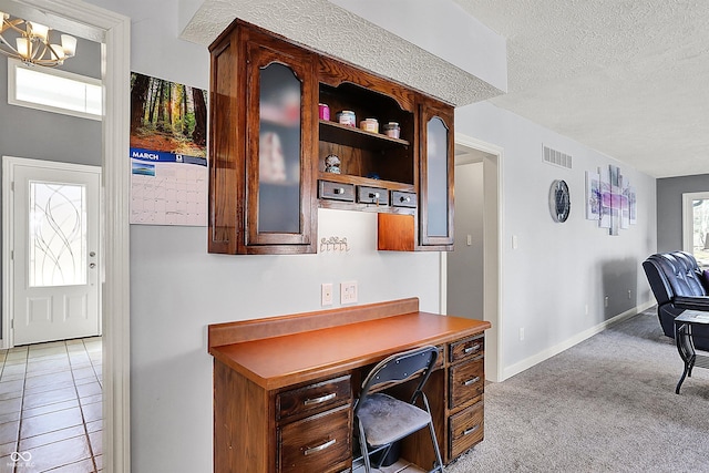 office area featuring visible vents, light carpet, a textured ceiling, an inviting chandelier, and baseboards