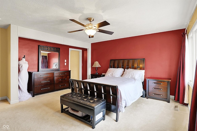 bedroom with a ceiling fan, light colored carpet, baseboards, and a textured ceiling