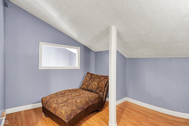 living area with baseboards, a textured ceiling, lofted ceiling, and wood finished floors