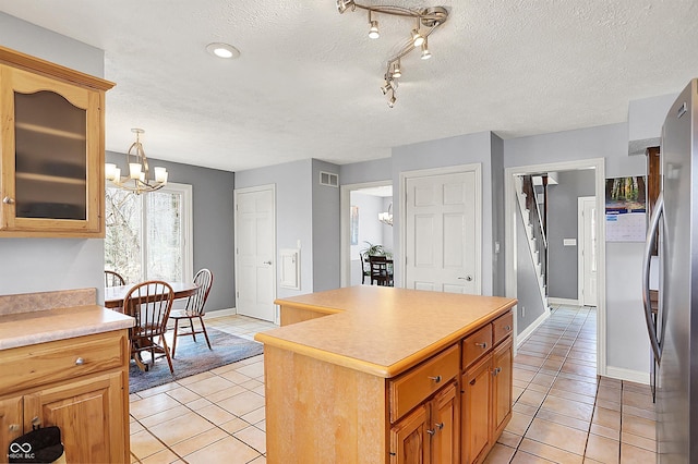 kitchen with light tile patterned floors, freestanding refrigerator, light countertops, a textured ceiling, and a notable chandelier