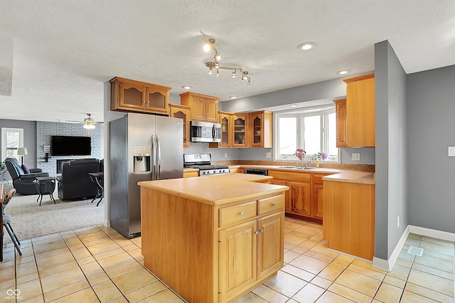 kitchen with light tile patterned floors, glass insert cabinets, appliances with stainless steel finishes, and a center island