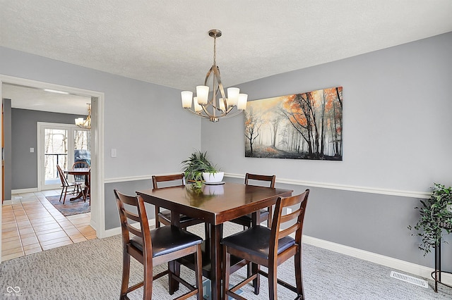 dining room with light carpet, a textured ceiling, light tile patterned floors, baseboards, and a chandelier