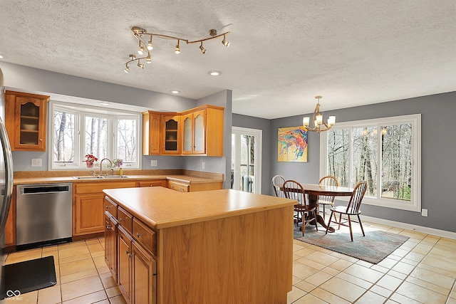 kitchen featuring glass insert cabinets, a chandelier, stainless steel dishwasher, light tile patterned flooring, and a sink