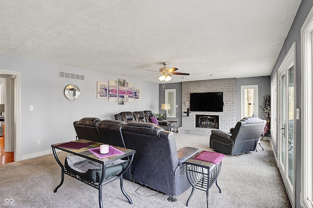 living room featuring visible vents, baseboards, carpet floors, a textured ceiling, and a ceiling fan