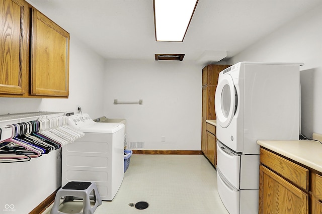 washroom featuring washer and clothes dryer, visible vents, cabinet space, and baseboards