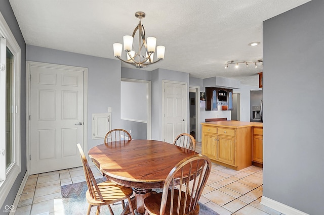 dining area with an inviting chandelier, light tile patterned flooring, baseboards, and a textured ceiling