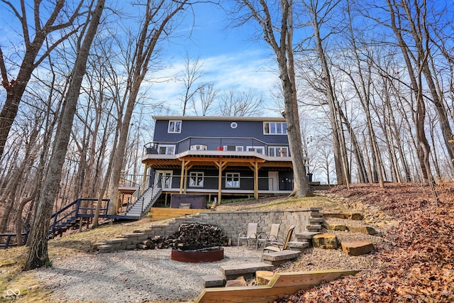 rear view of house with a wooden deck, an outdoor fire pit, and stairs