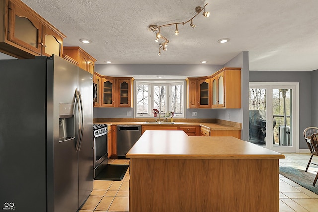 kitchen with light tile patterned floors, appliances with stainless steel finishes, a sink, and a healthy amount of sunlight