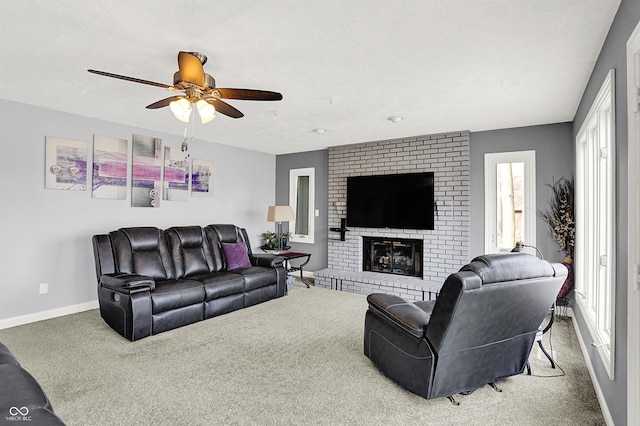 living area featuring a brick fireplace, baseboards, carpet flooring, a textured ceiling, and a ceiling fan