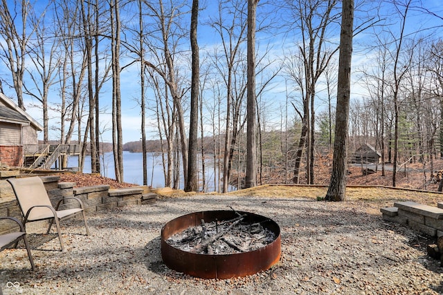 view of yard with a water view, stairs, and an outdoor fire pit