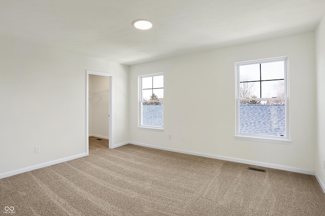 empty room featuring visible vents, carpet, and baseboards