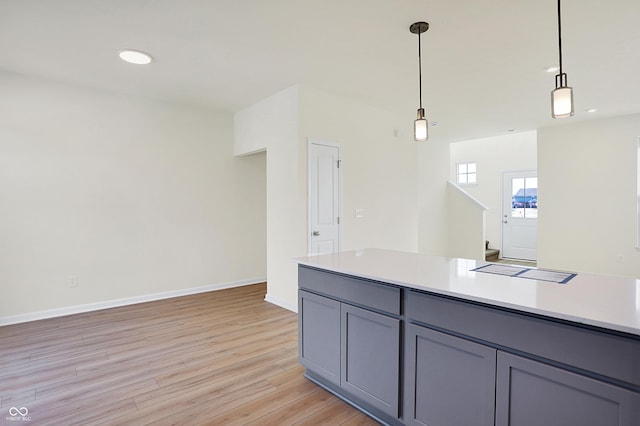 kitchen with decorative light fixtures, light wood-type flooring, gray cabinetry, and light countertops