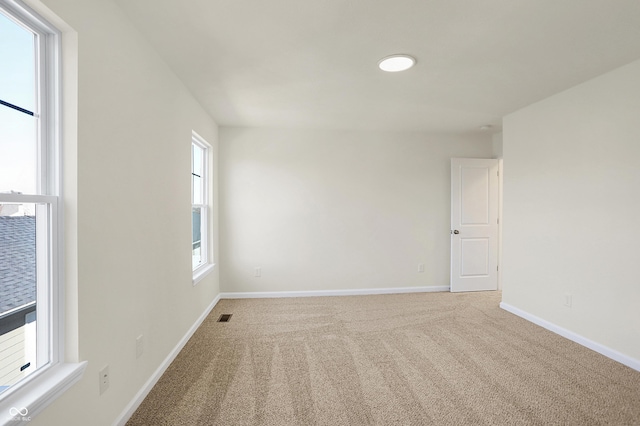 carpeted empty room featuring baseboards and visible vents