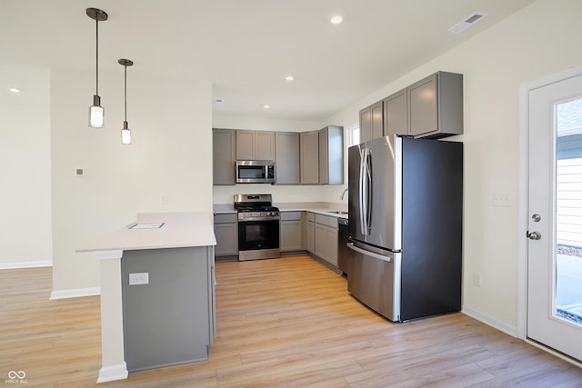 kitchen featuring visible vents, a peninsula, light wood-style flooring, gray cabinets, and appliances with stainless steel finishes