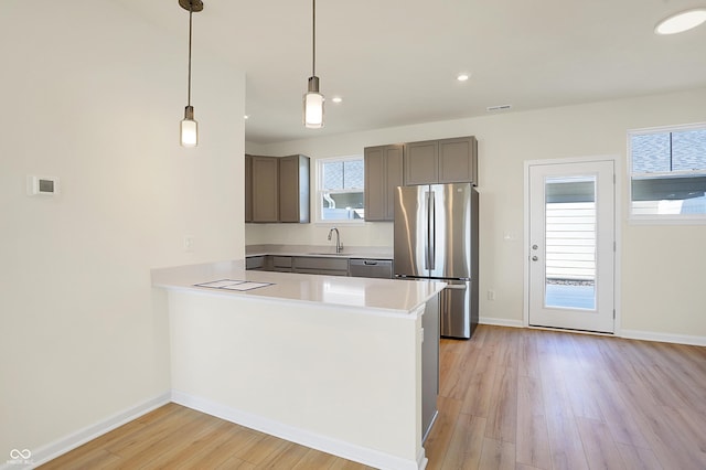 kitchen featuring a wealth of natural light, stainless steel appliances, light countertops, and a sink