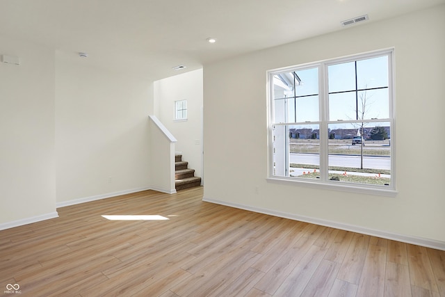 unfurnished living room featuring visible vents, stairs, light wood-type flooring, and baseboards