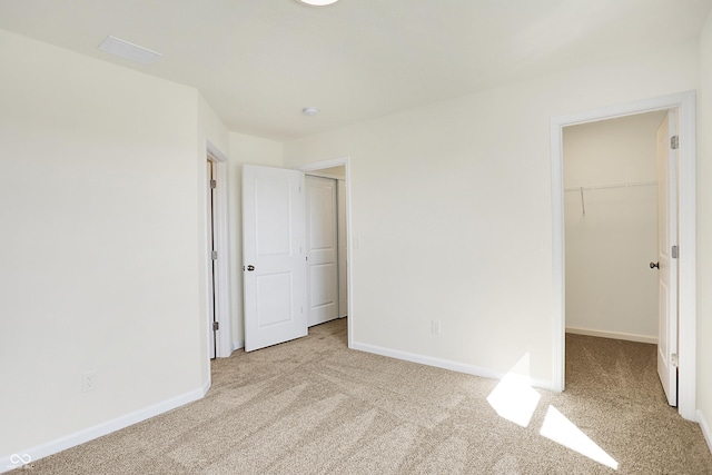 unfurnished bedroom with a closet, baseboards, carpet, and a spacious closet