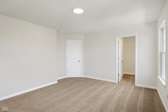 unfurnished bedroom featuring a closet, baseboards, carpet floors, and a spacious closet